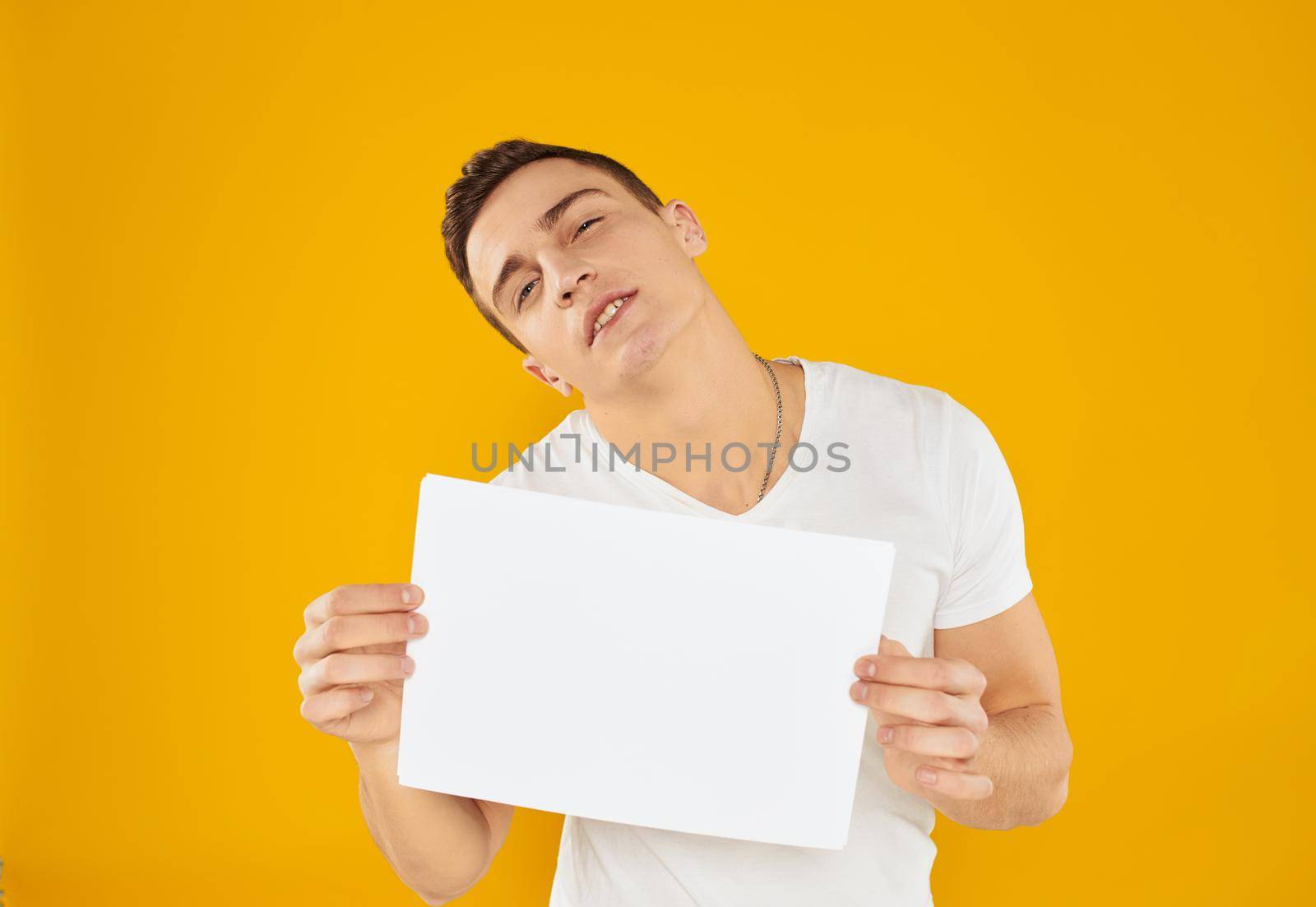 Guy with white sheet of paper mockup yellow background Copy Space. High quality photo