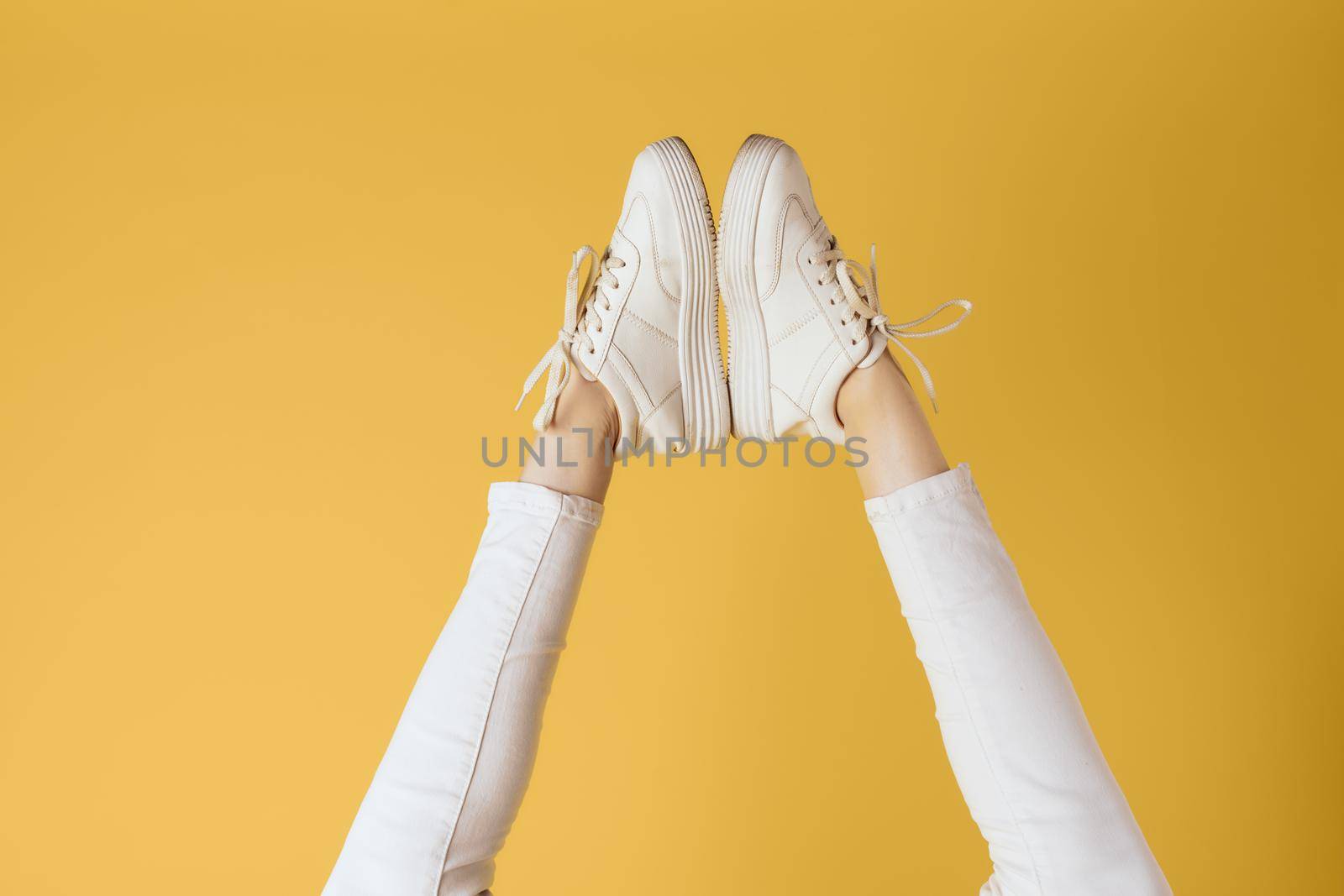 Womens legs white pants and sneakers fashion studio elegant style. High quality photo