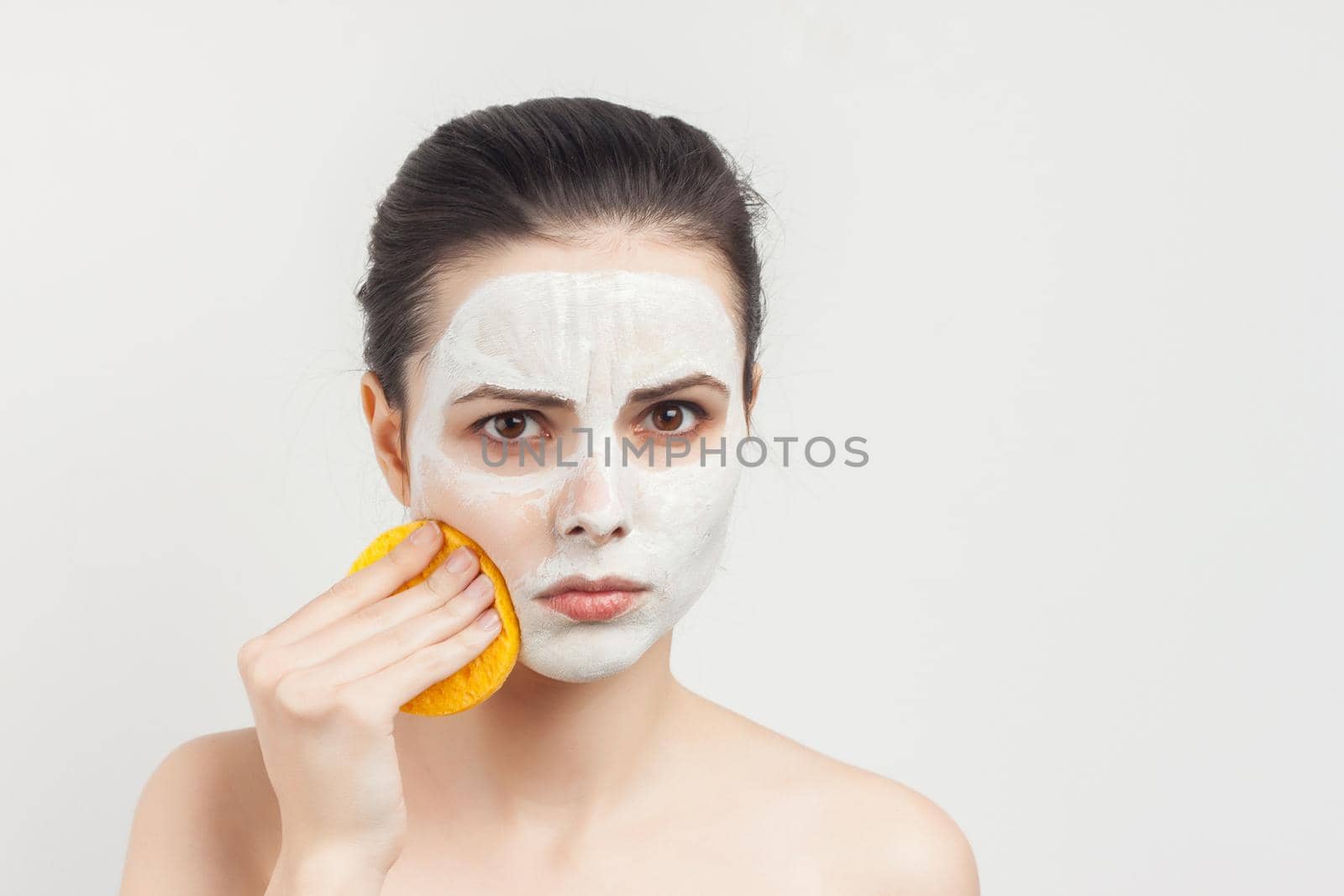 woman with bare shoulders cream mask on face scrub sponges. High quality photo