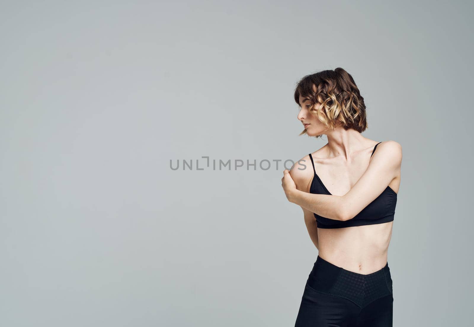 Woman in dark sportswear on gray background gesturing with hands cropped view by SHOTPRIME