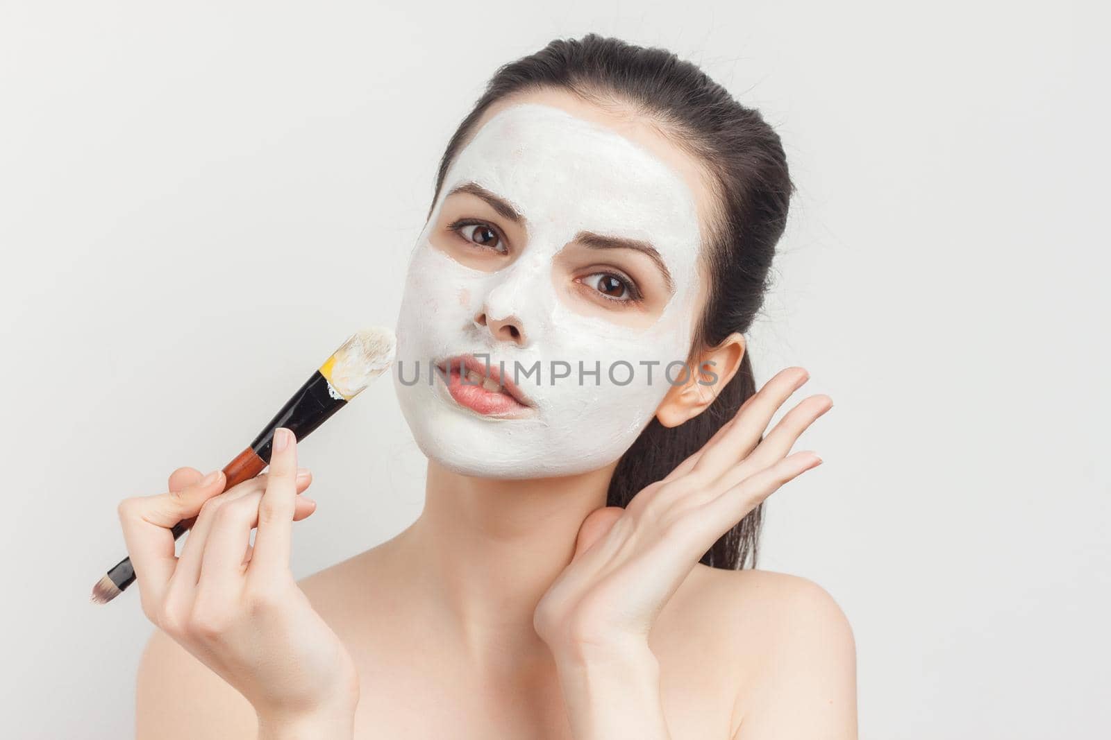 emotional brunette cream face mask bare shoulders cropped view clear skin. High quality photo