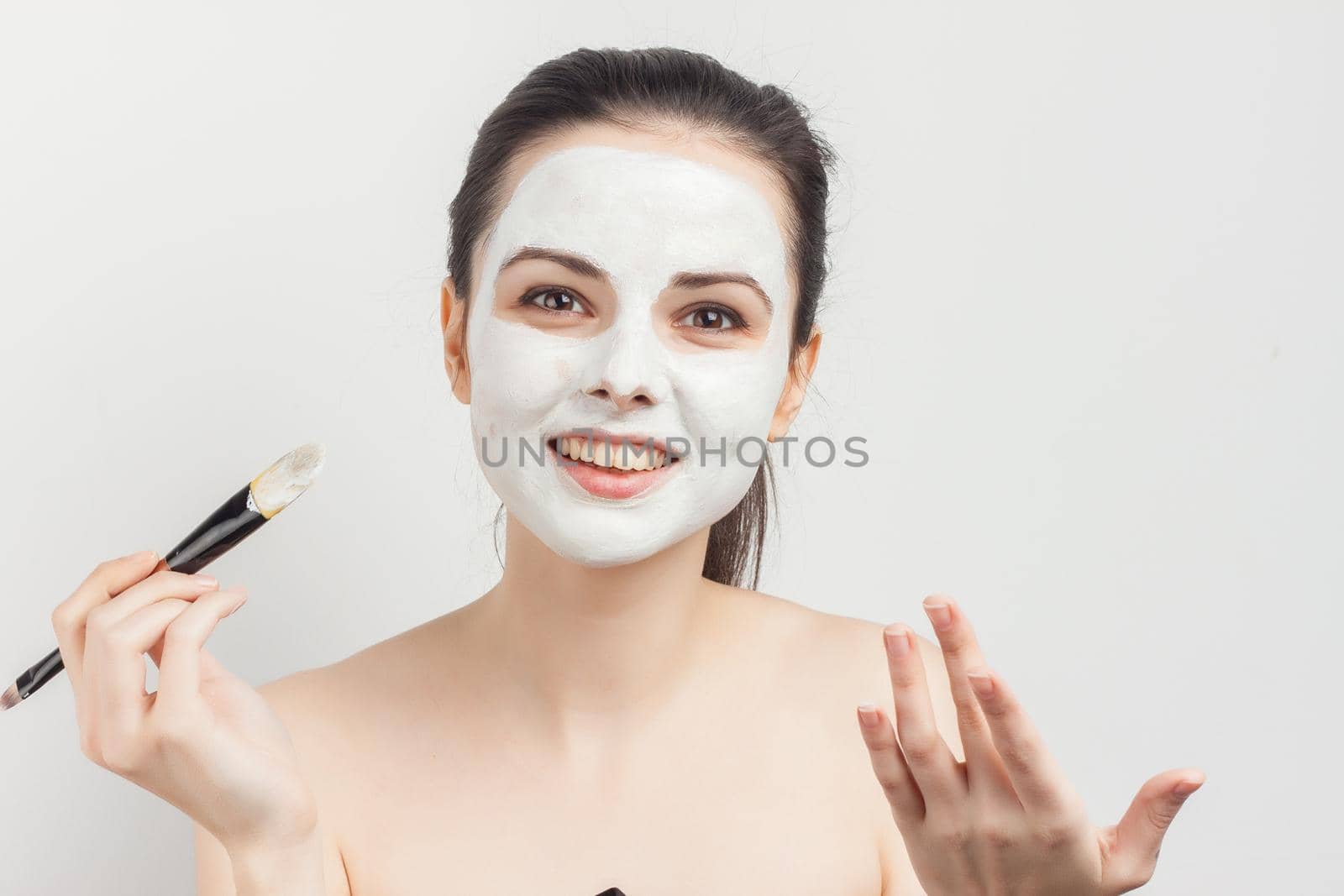 brunette brushing cream on face skin care cropped view. High quality photo