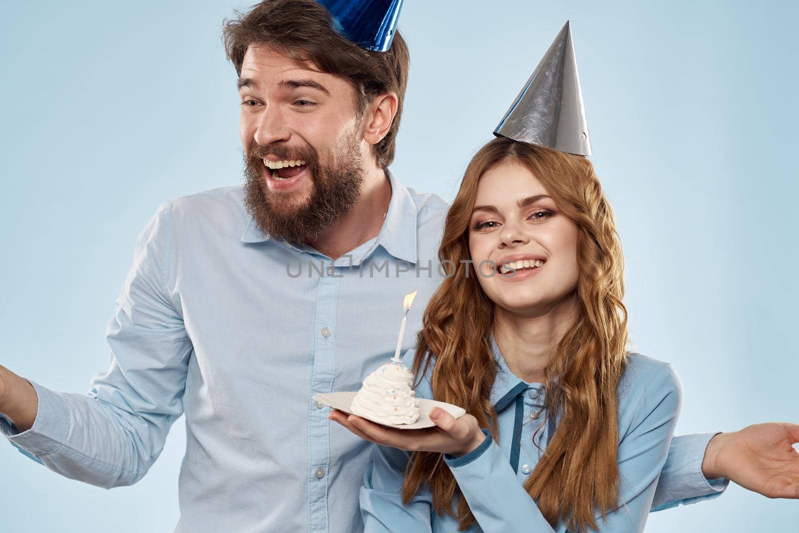 Cheerful man and woman with cake in a plate corporate party blue background. High quality photo