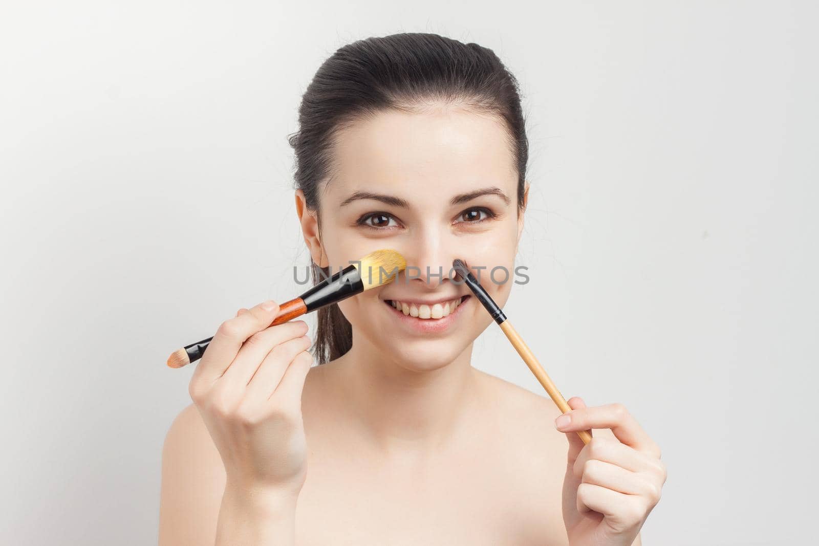 woman with bare shoulders face cream makeup brush in hand. High quality photo