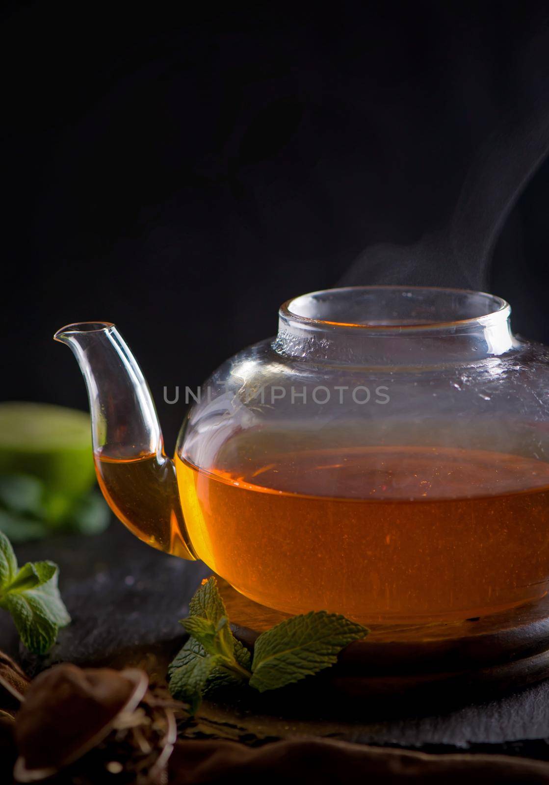 Teapot with tea surrounded with green leaves, tea ceremony, green tea in a transparent cup