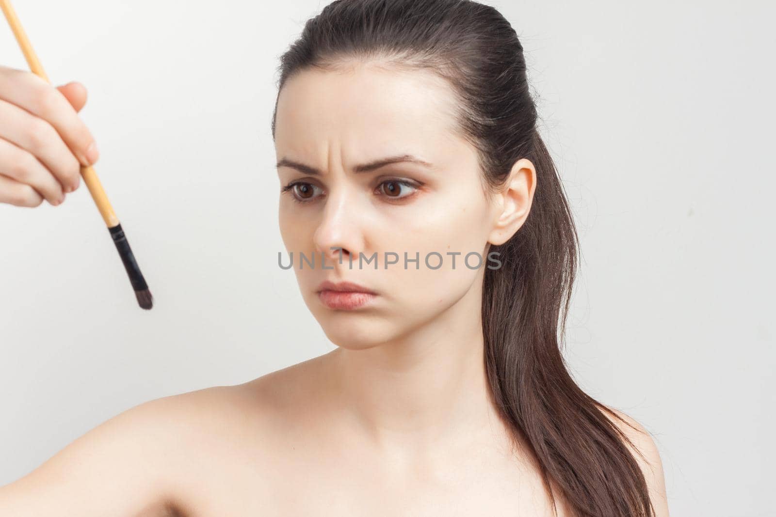 woman with bare shoulders face cream makeup brush in hand. High quality photo