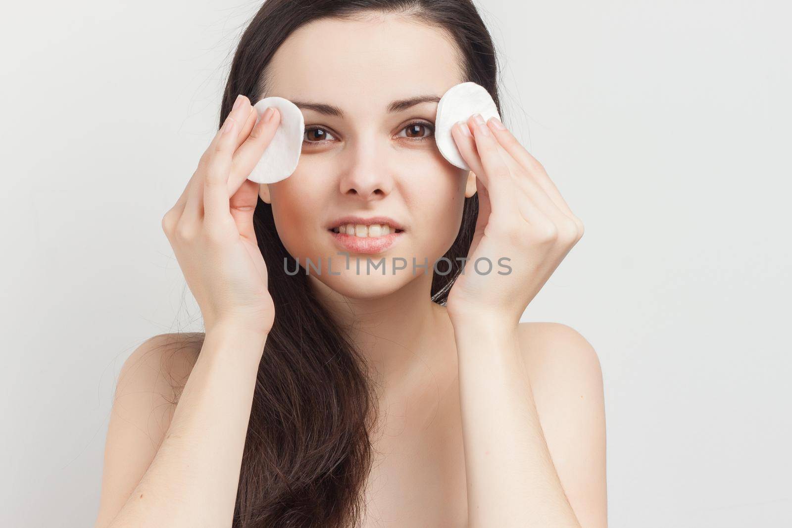 brunette with flowing hair naked shoulders sponge near face. High quality photo