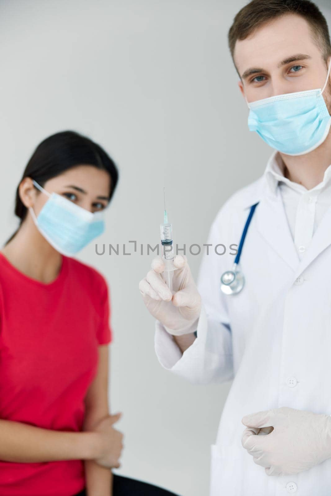 male doctor holding a syringe in his hands next to a patient injection vaccination by SHOTPRIME