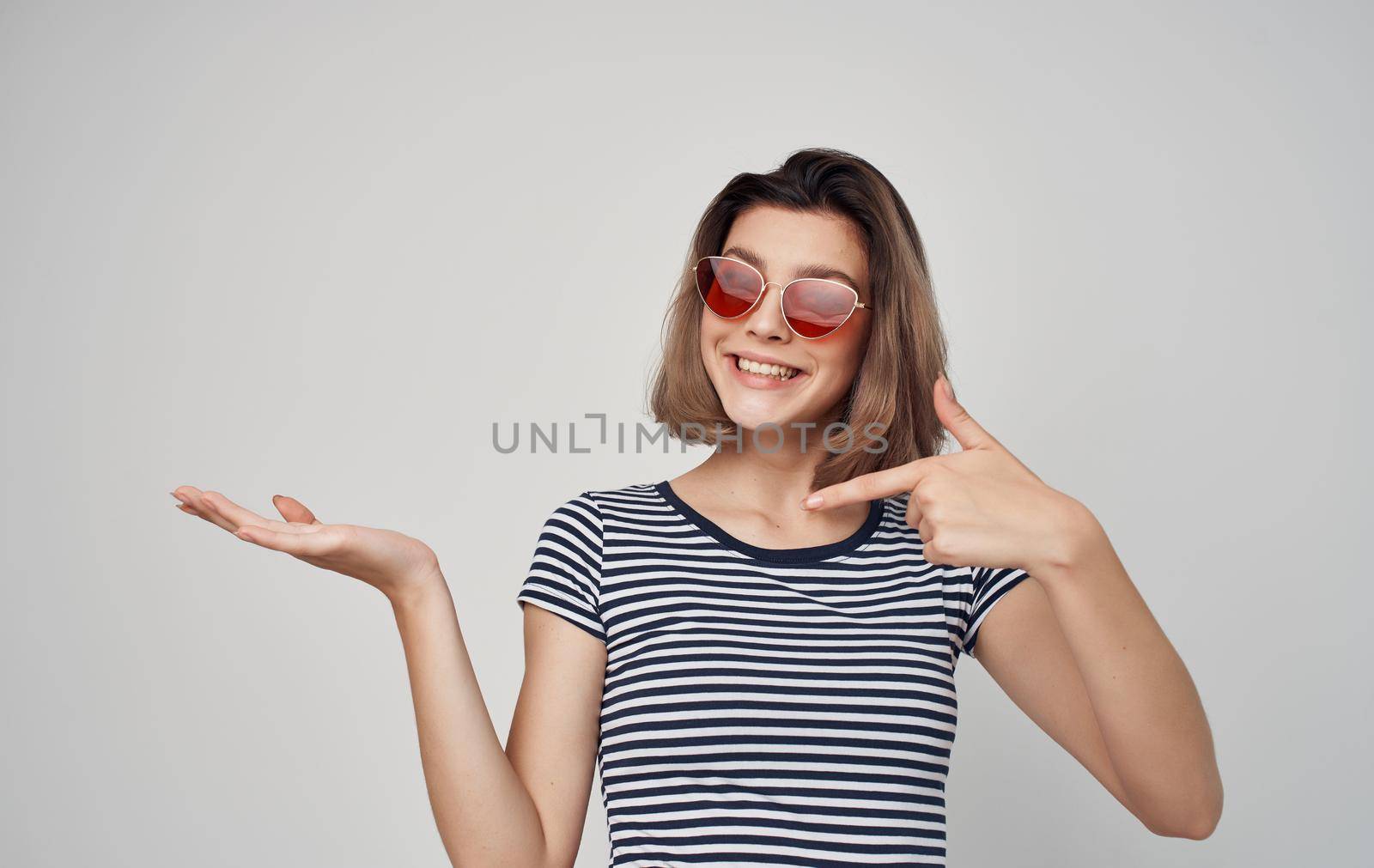 pretty woman in fashion clothes red skirt striped t-shirt sunglasses gesturing with hands. High quality photo