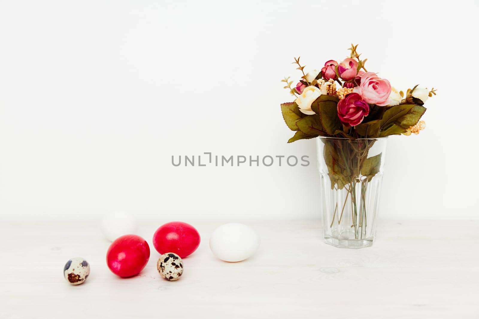 red eggs Easter holiday of the resurrection of Christ and a bouquet of flowers in a vase. High quality photo
