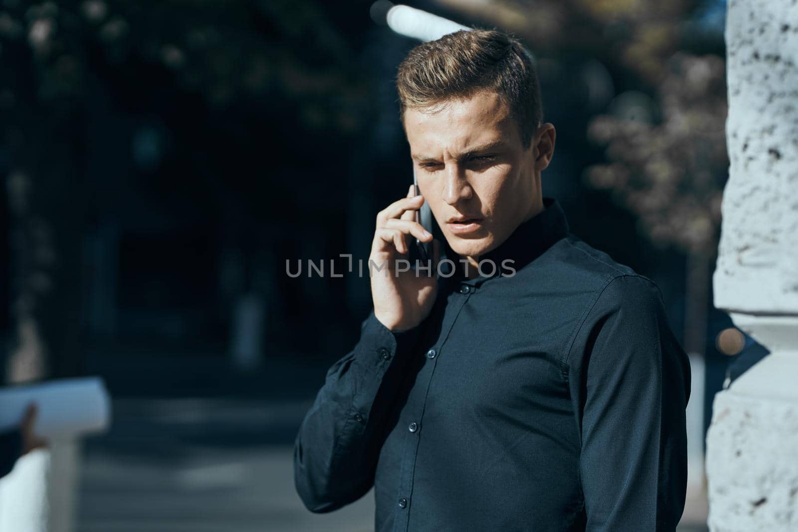 business man in a black shirt on the street talking on the phone. High quality photo