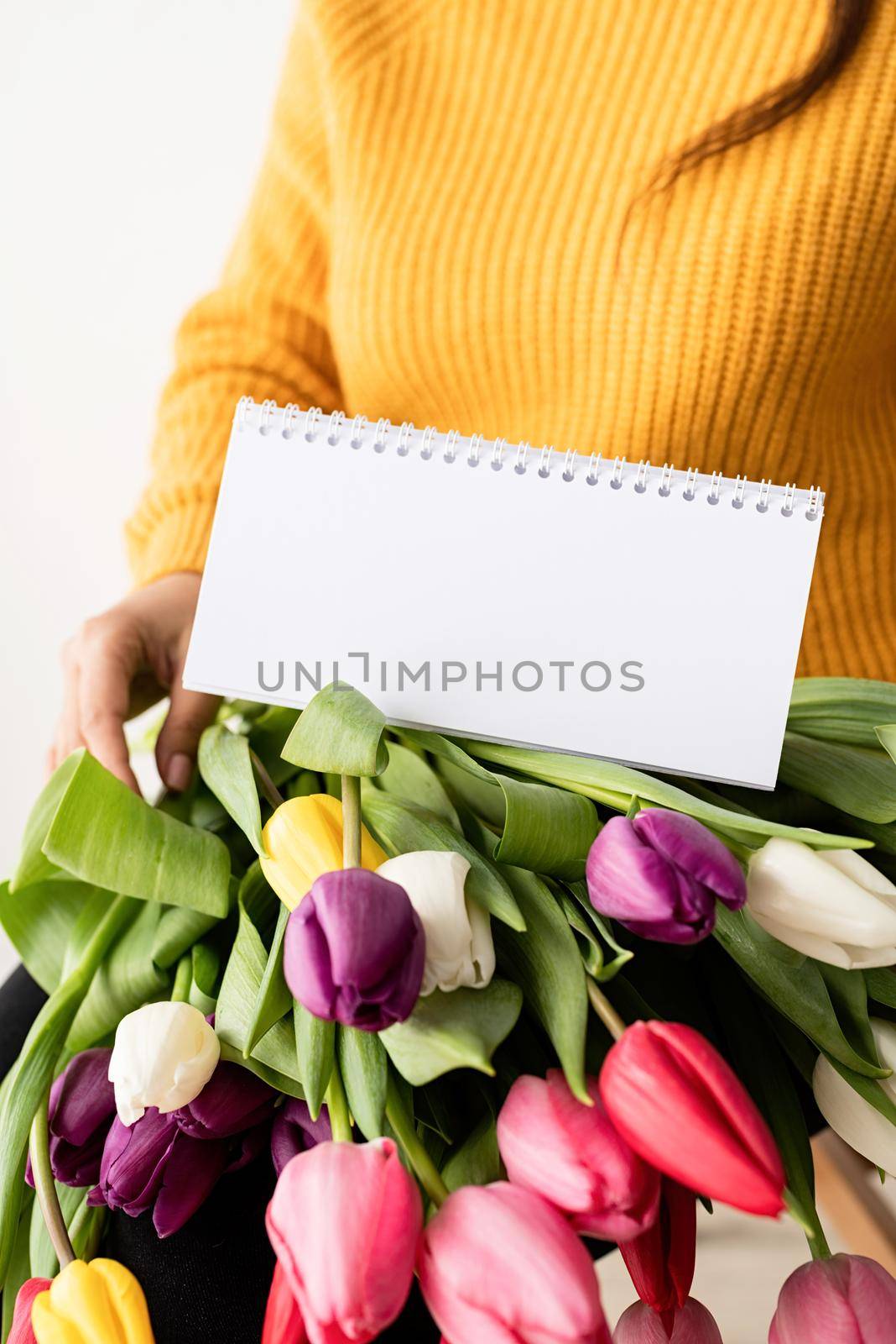Beautiful young brunette woman with bouquet of fresh pink tulips and blank calendar for mock up by Desperada