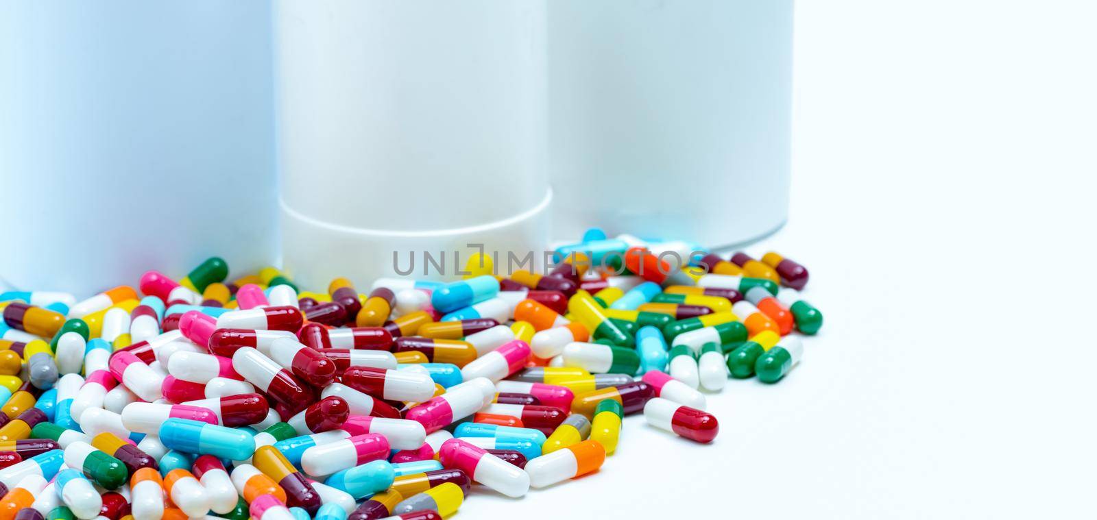 Pile of colorful antibiotic capsule pills on blurred plastic drug bottles. Antibiotic drug resistance concept. Antibiotic drugs smart use. Drug interactions. Pharmaceutical industry. Polypharmacy.