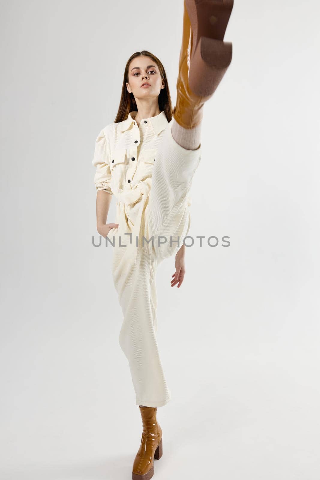 pretty woman in suit holds hand in pocket moda studio light background. High quality photo