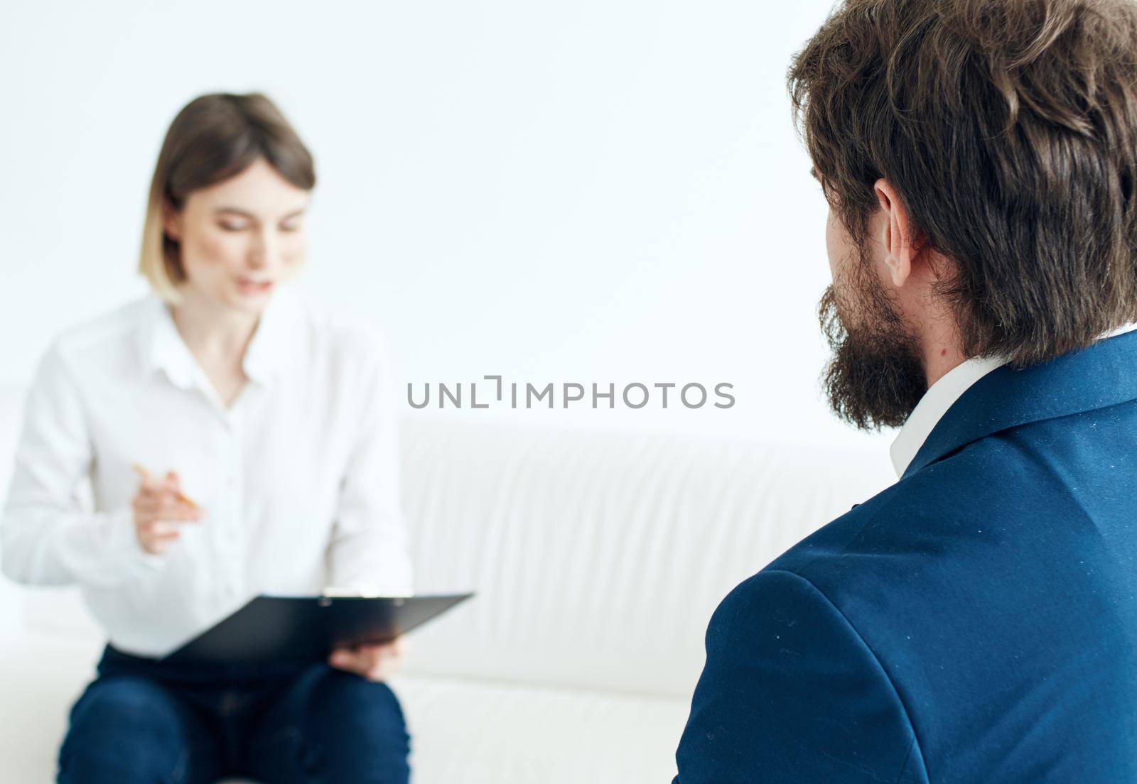 Business woman in a shirt sits on the couch and the man documents the model of a job. High quality photo