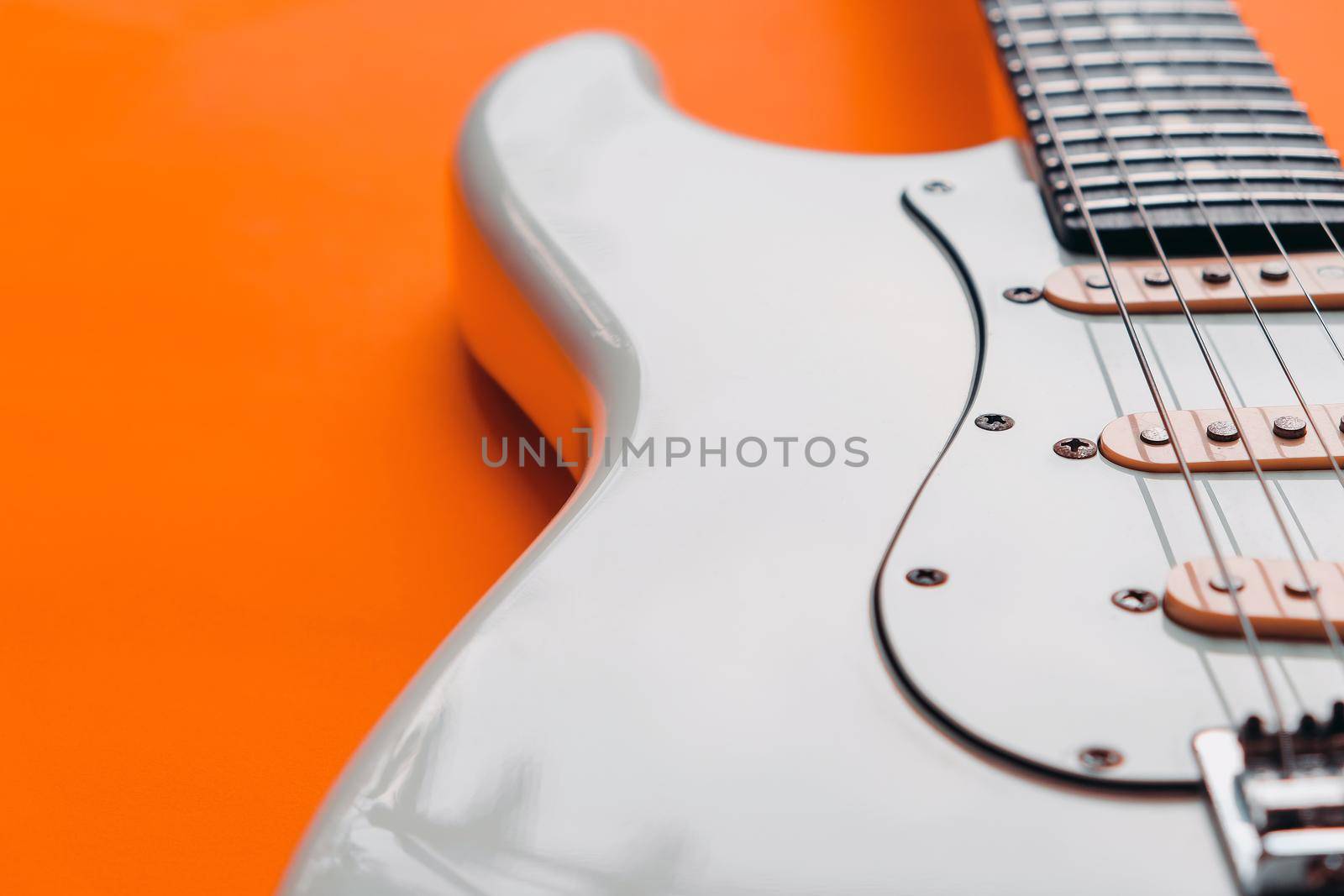Detail of White Electric Guitar on a orange background.