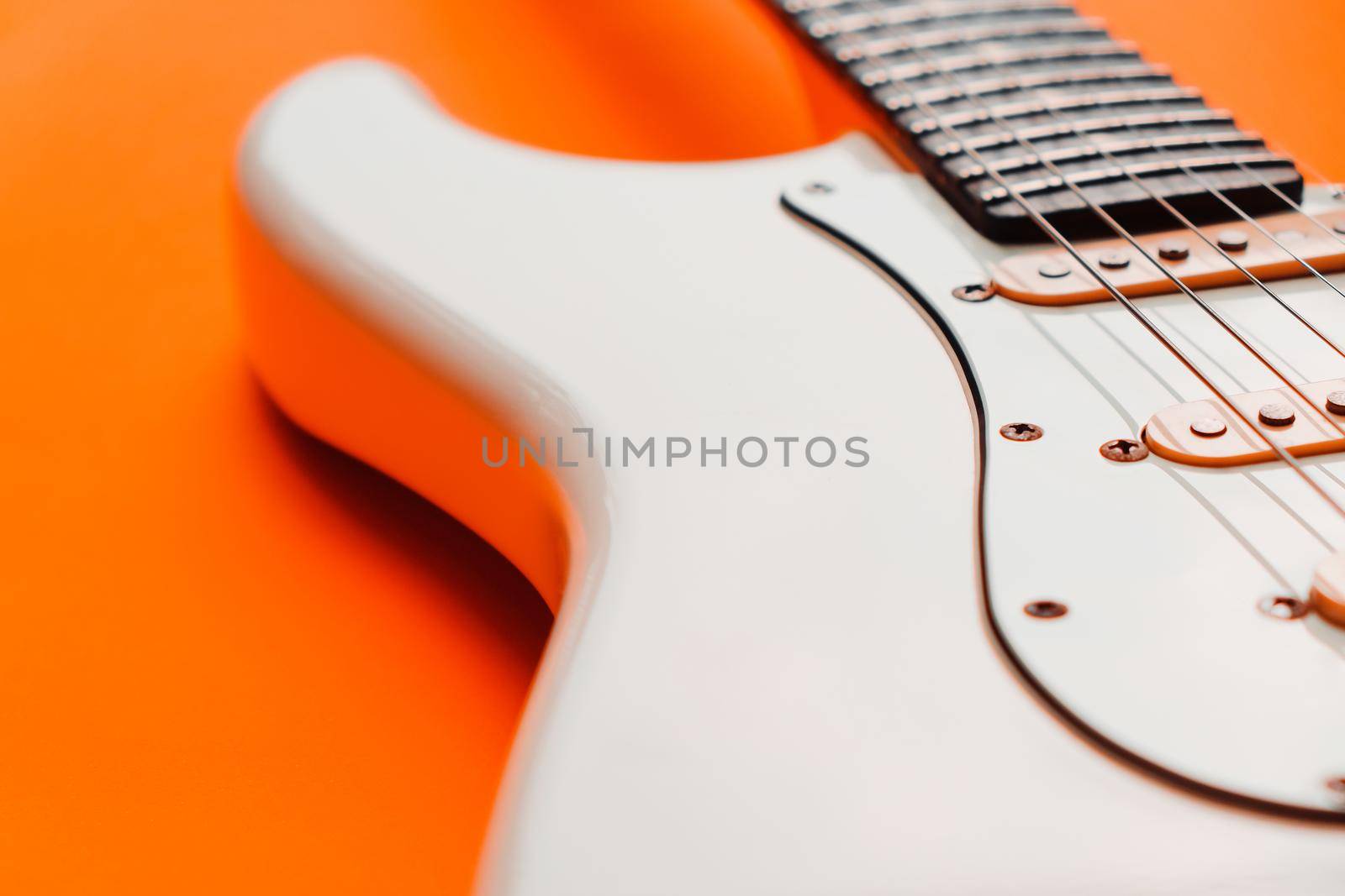 Detail of White Electric Guitar on a orange background.