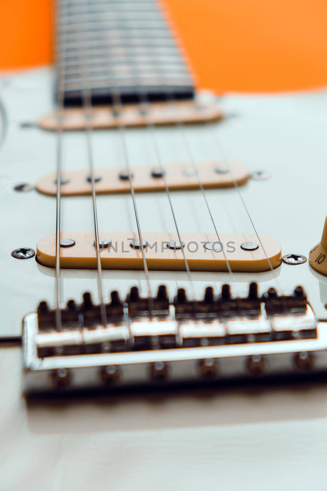 Detail of White Electric Guitar on a orange background.