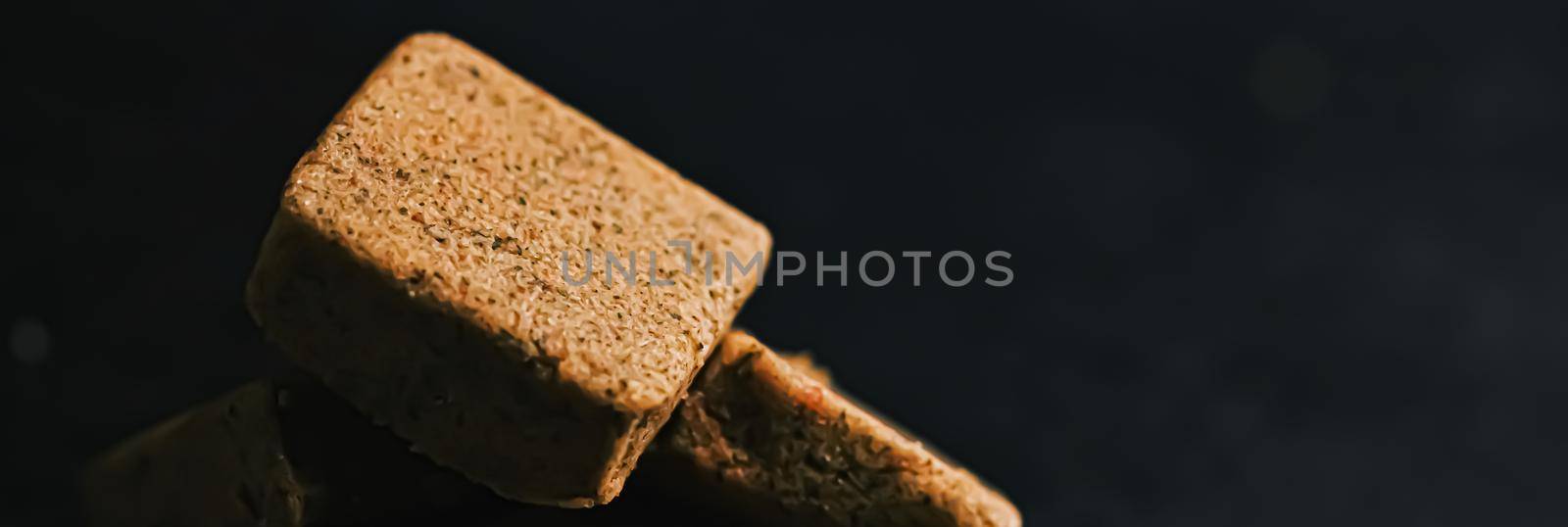 Vegetable bouillon cubes on stone kitchen board, stock or broth ingredient for soup, closeup