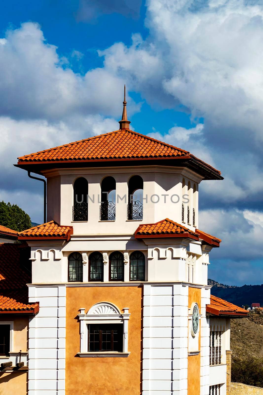 The tower is white with a clock in a tory style. Sunny summer day. Front view. by Essffes