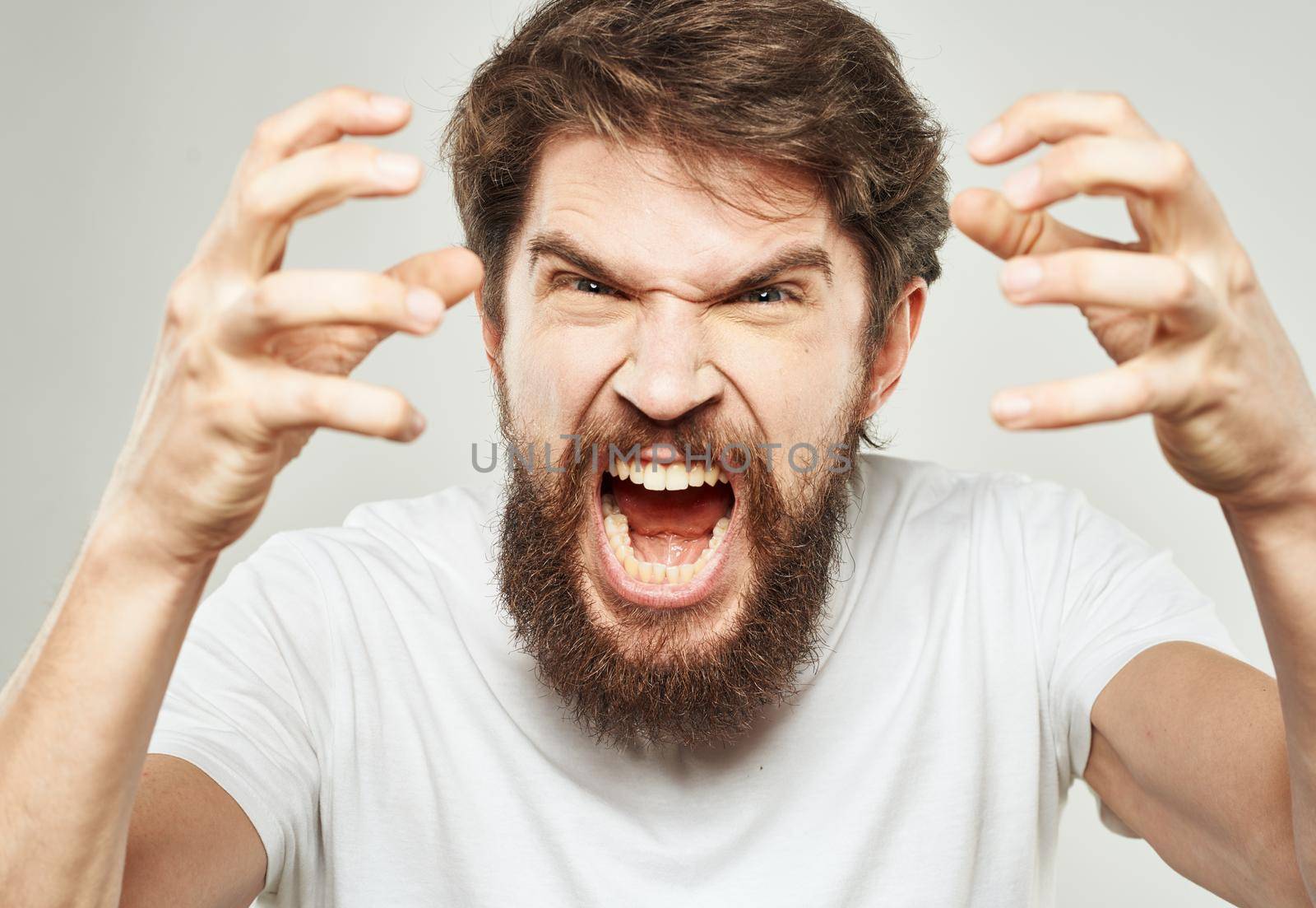Aggressive man yells against a light background and gestures with his hands cropped view. High quality photo