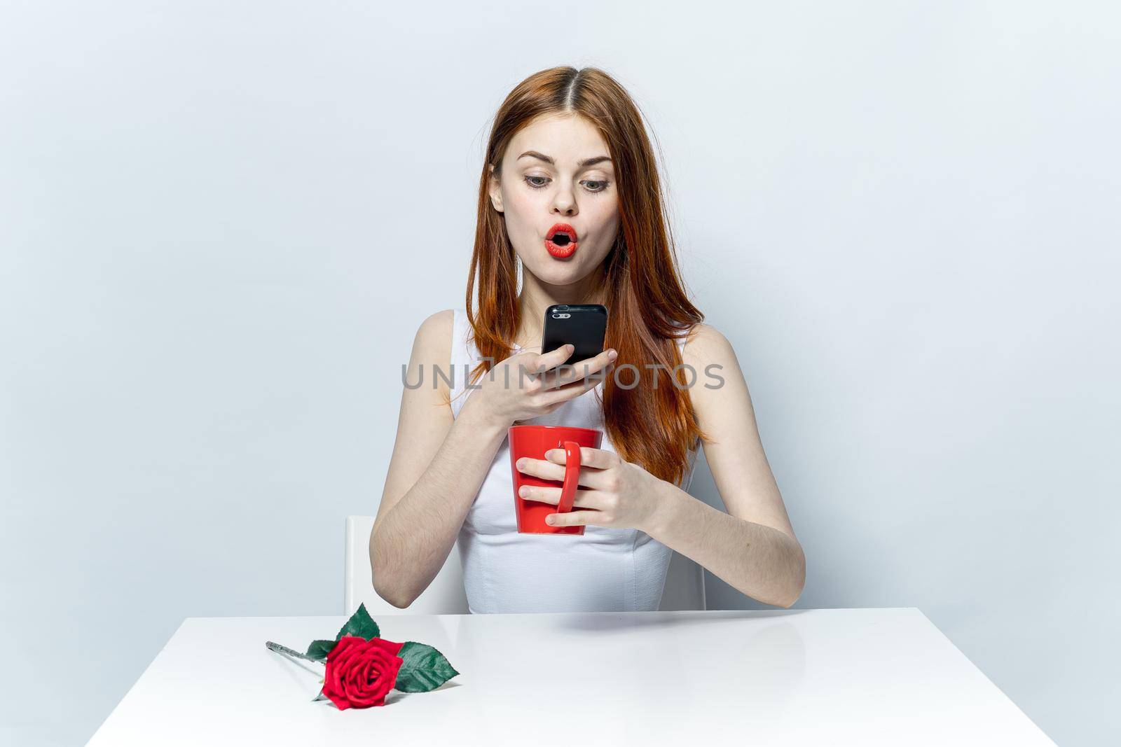 pretty woman sitting at a table with a phone in her hands emotions communication mug with a drink by SHOTPRIME