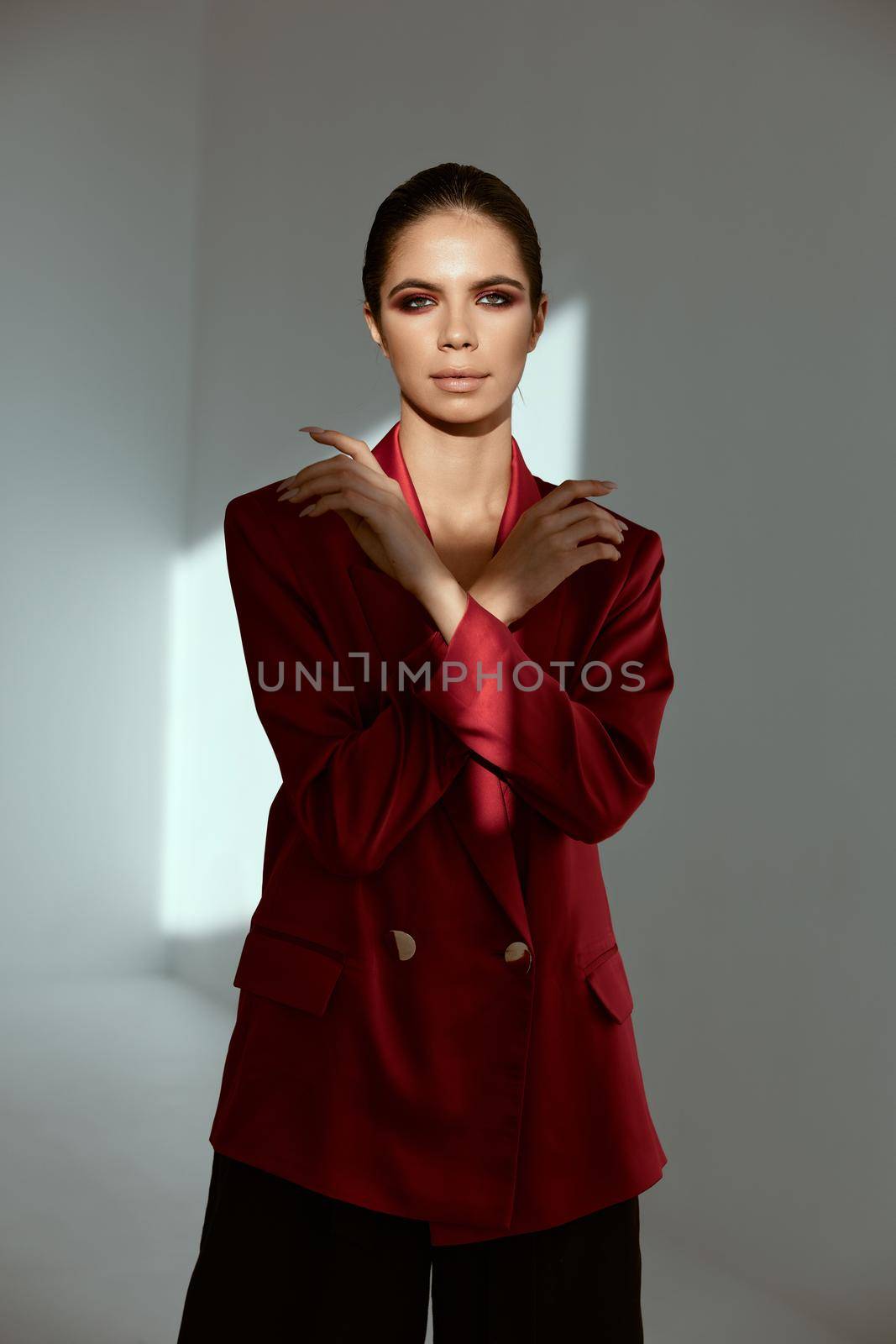 attractive brunette in red jacket holds hands near face charm model. High quality photo