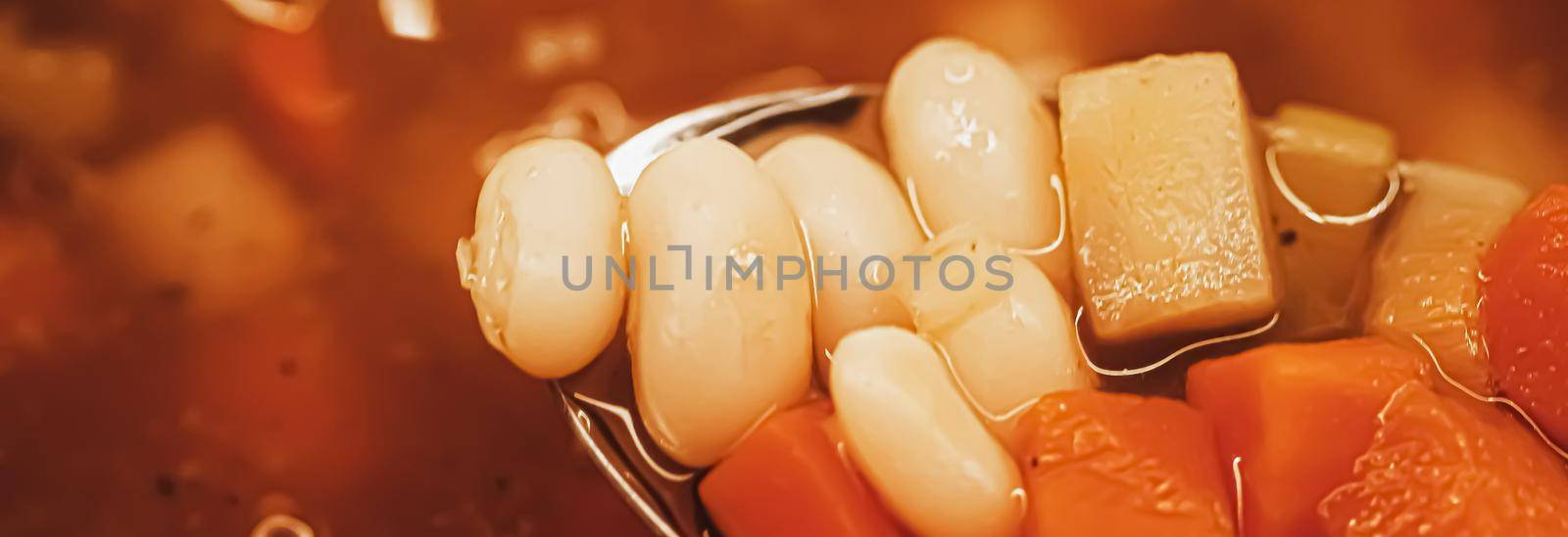 Vegetable soup with beans boiling in a saucepan, homemade food closeup