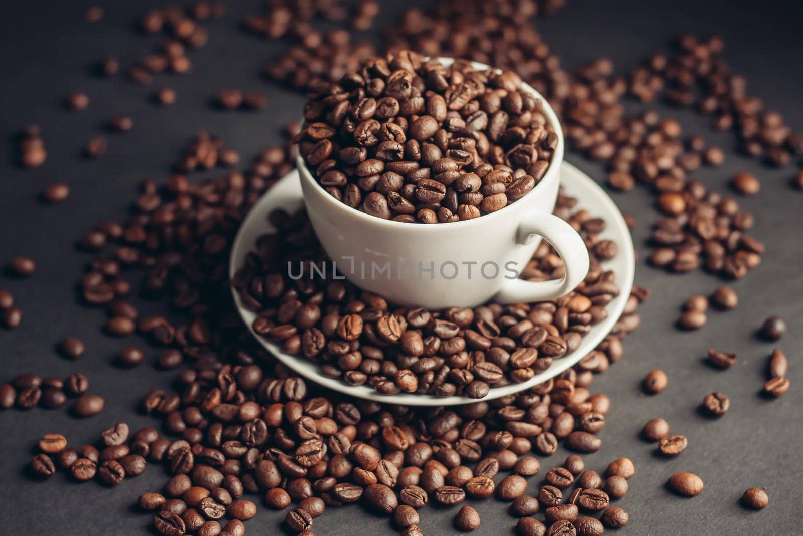 saucer with coffee beans and white cup on gray table close-up. High quality photo