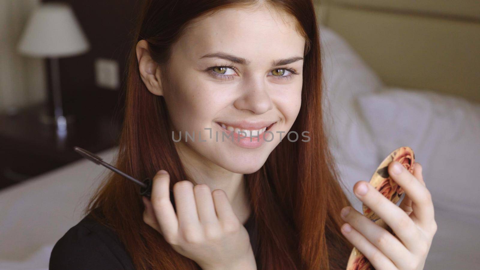 woman in bedroom apply makeup on face eyelashes personal care. High quality photo