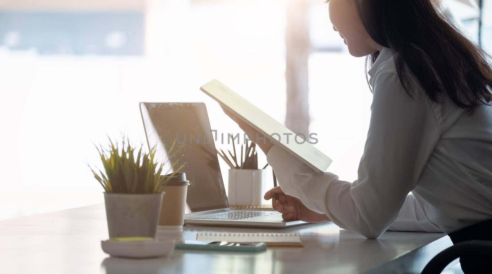 Photo of cheerful joyful asian woman using tablet for data analysis on working space by nateemee