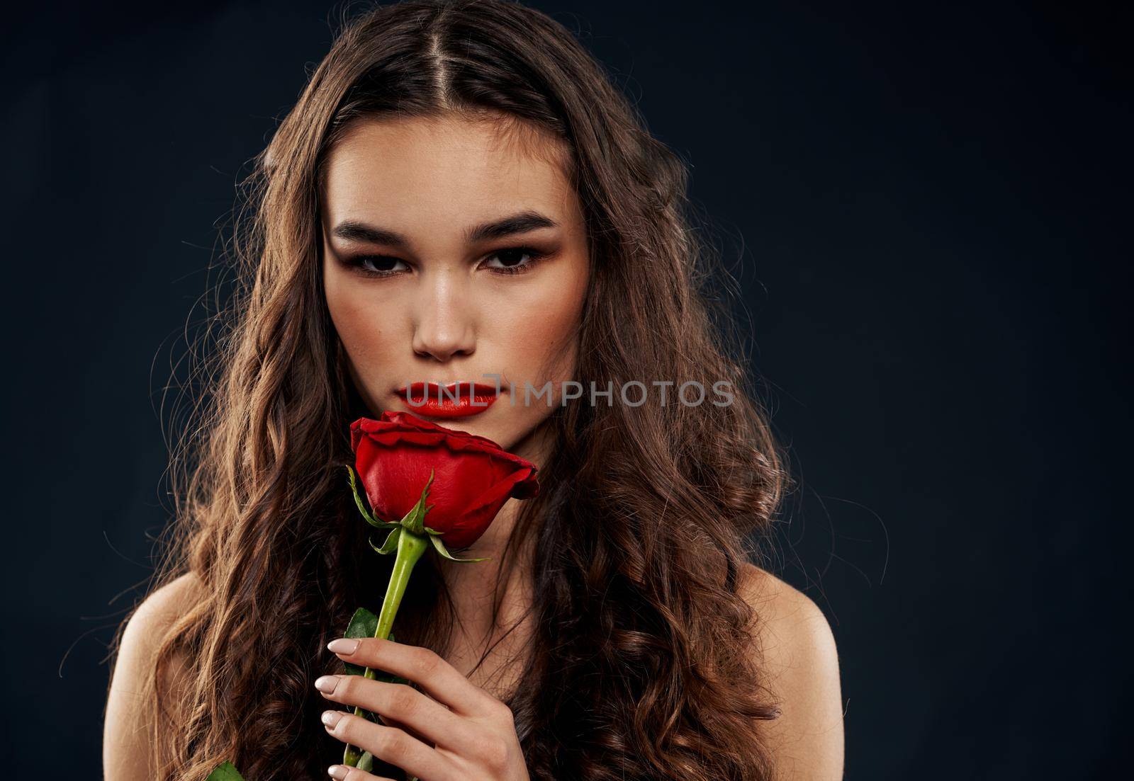 Romantic woman on a black background with a red flower. High quality photo