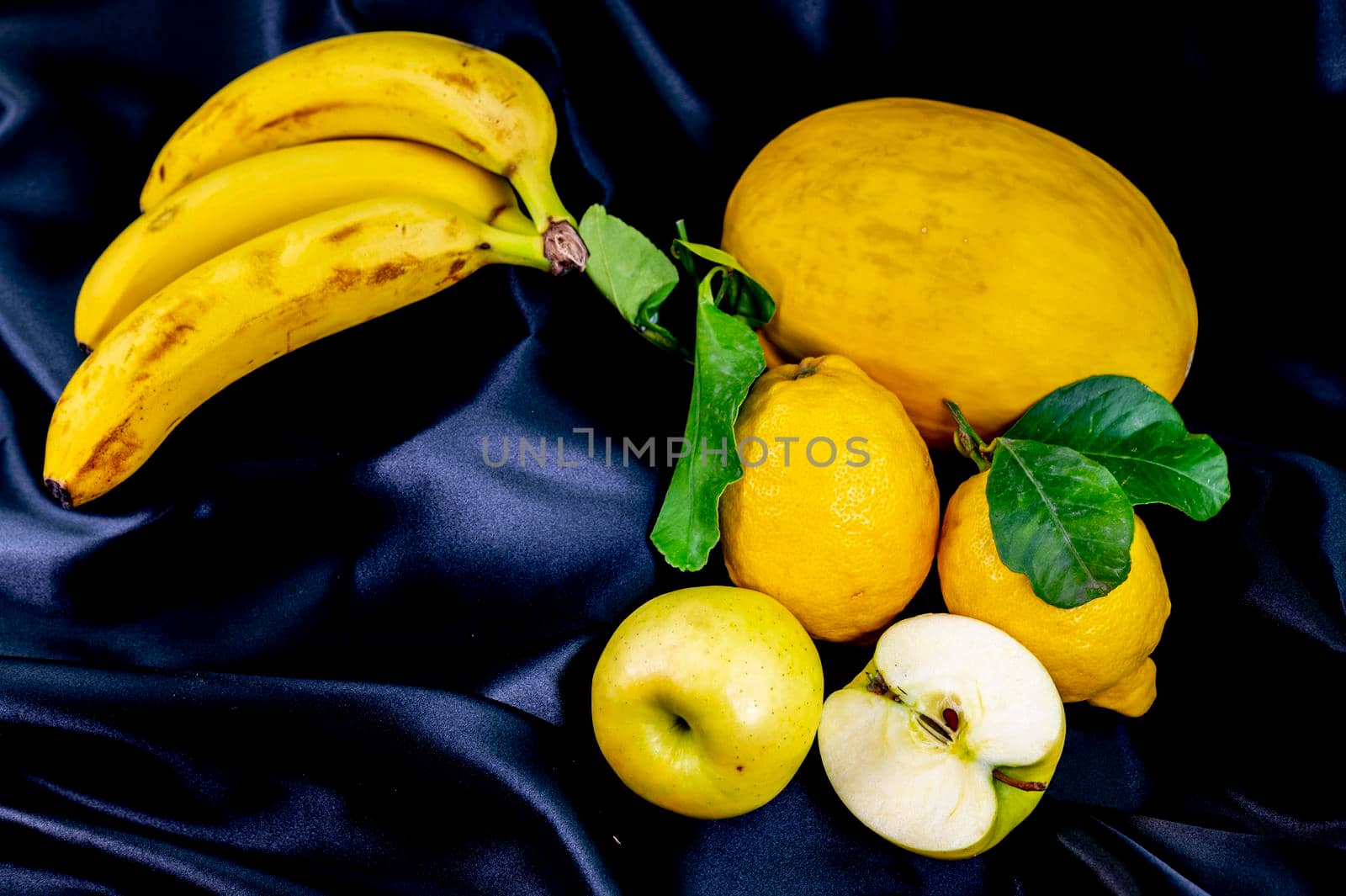 yellow fruit on a black background with melon bananas apples and lemons