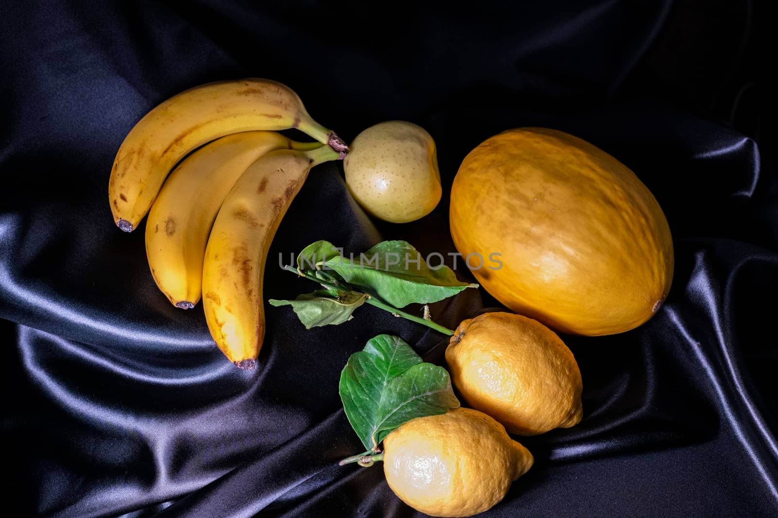 yellow fruit on a black background with melon bananas apples and lemons