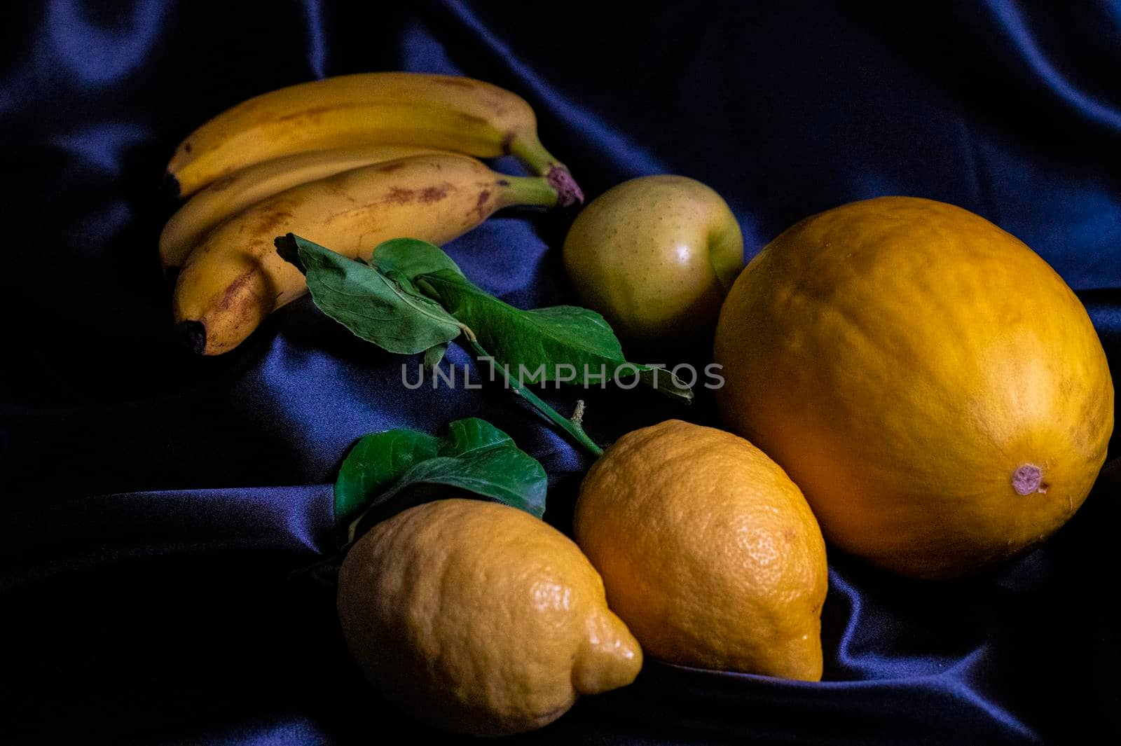 yellow fruit on a black background with melon bananas apples and lemons