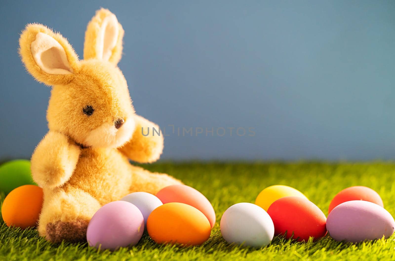 Colorful easter eggs and bunny on grass with blue background