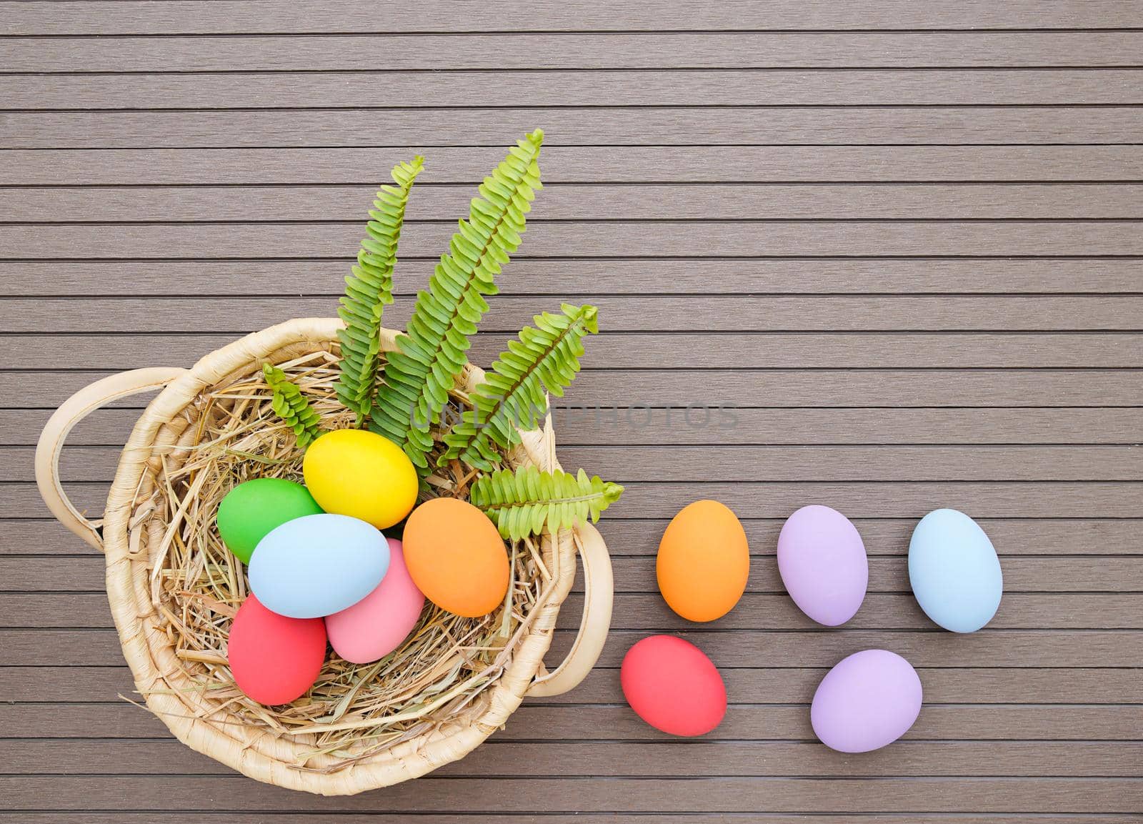 Colorful easter eggs in the basket on wood background with space