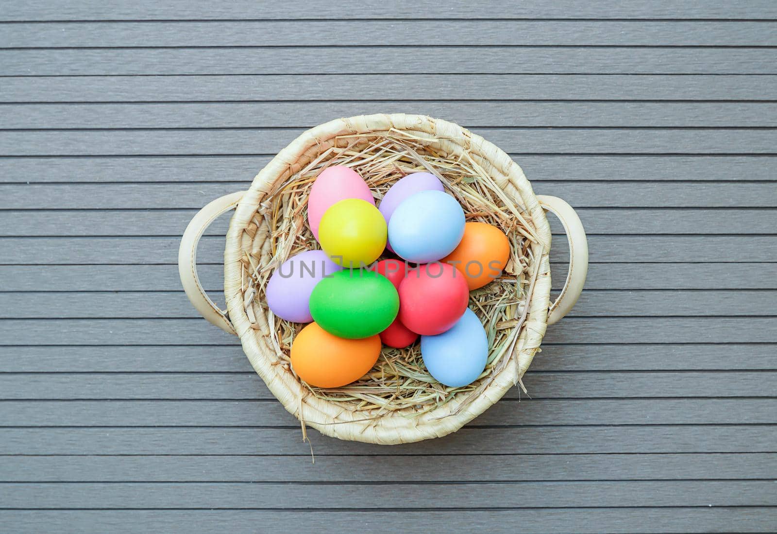 Colorful easter eggs in the basket on wood background with space