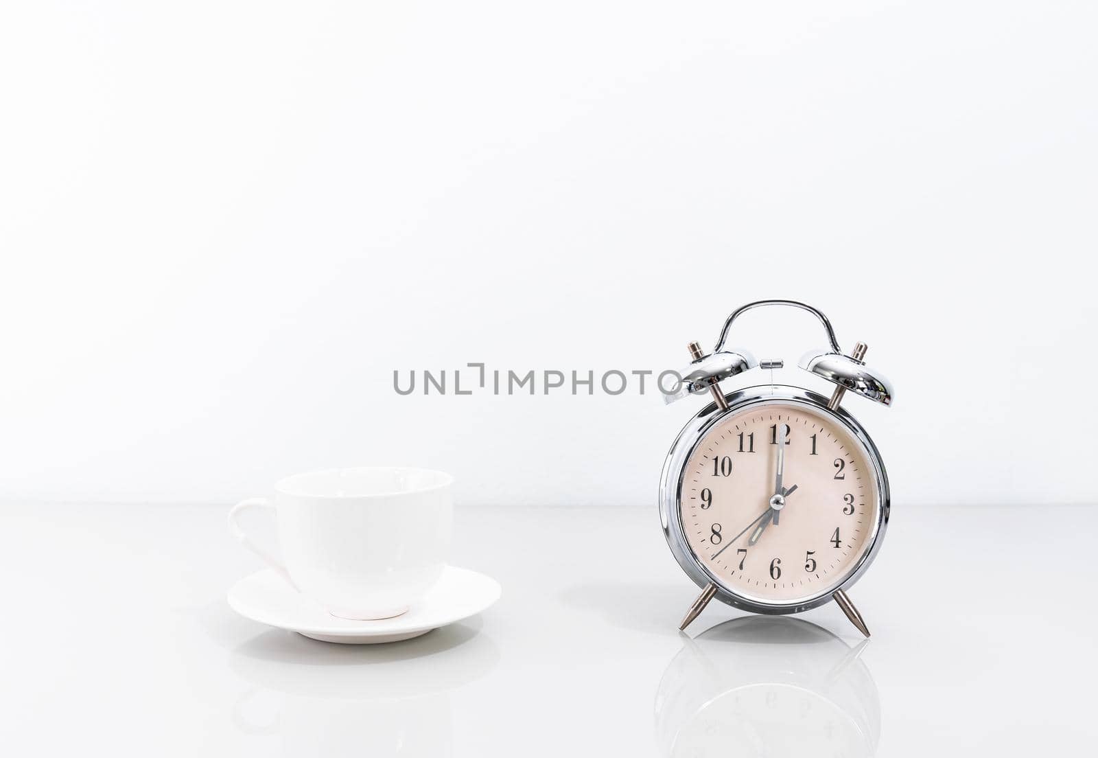 Silver alarm clock and coffee cup on table