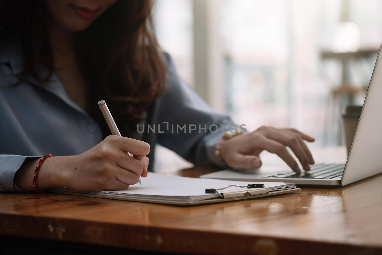 Closeup image of a woman's hand writing down on a white blank notebook on table . High quality photo