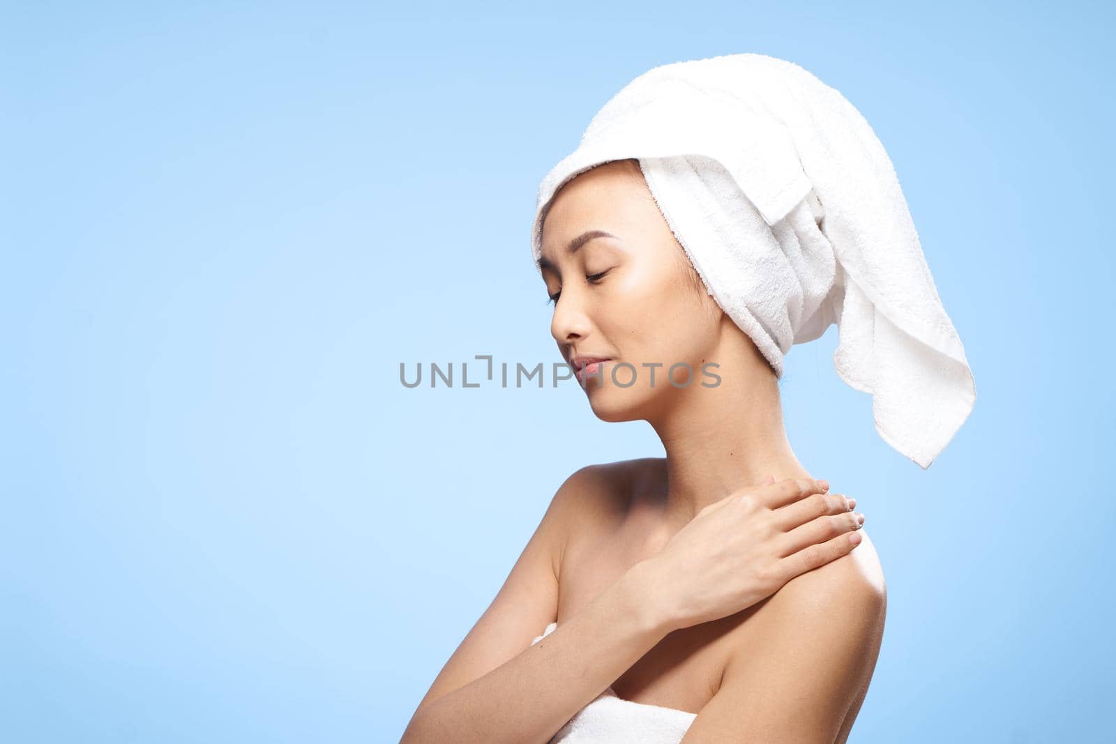 woman of asian appearance bare shoulders towel on head shower rest. High quality photo