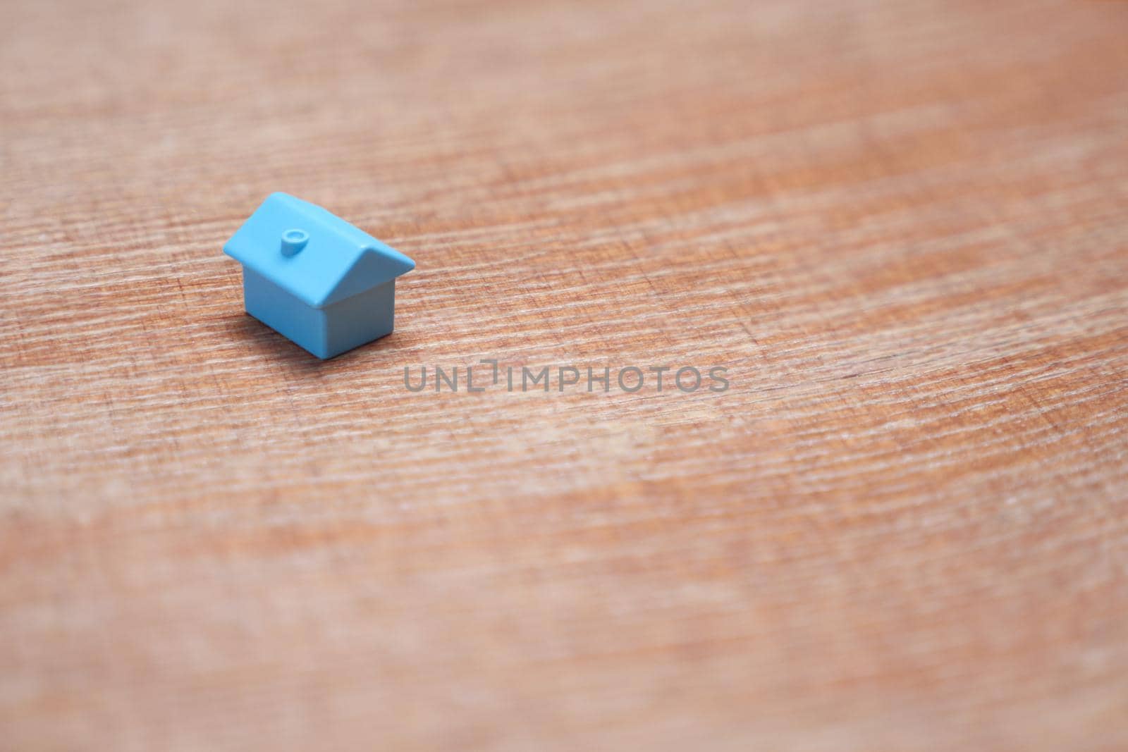 Symbol of house on wood background. Real estate buy sell home icon property house model. Blue toy home property market housing mortgage loan. Minimal design one single miniature house with copy space