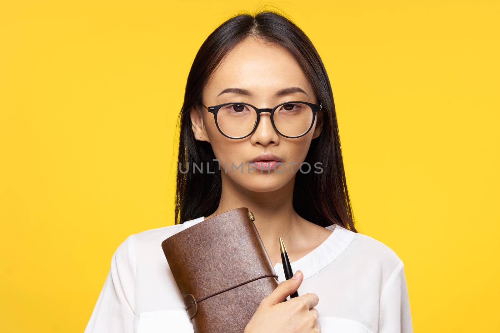 woman of asian appearance with notepad in hand glasses elegant style manager yellow background. High quality photo