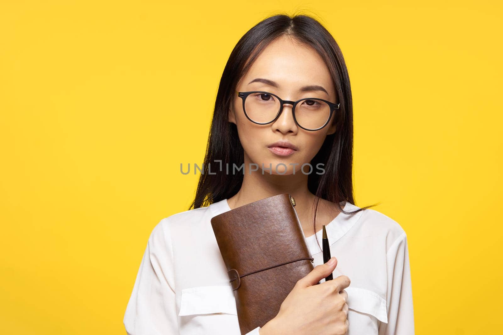 woman of asian appearance with notepad in hands and pen glasses elegant style work. High quality photo