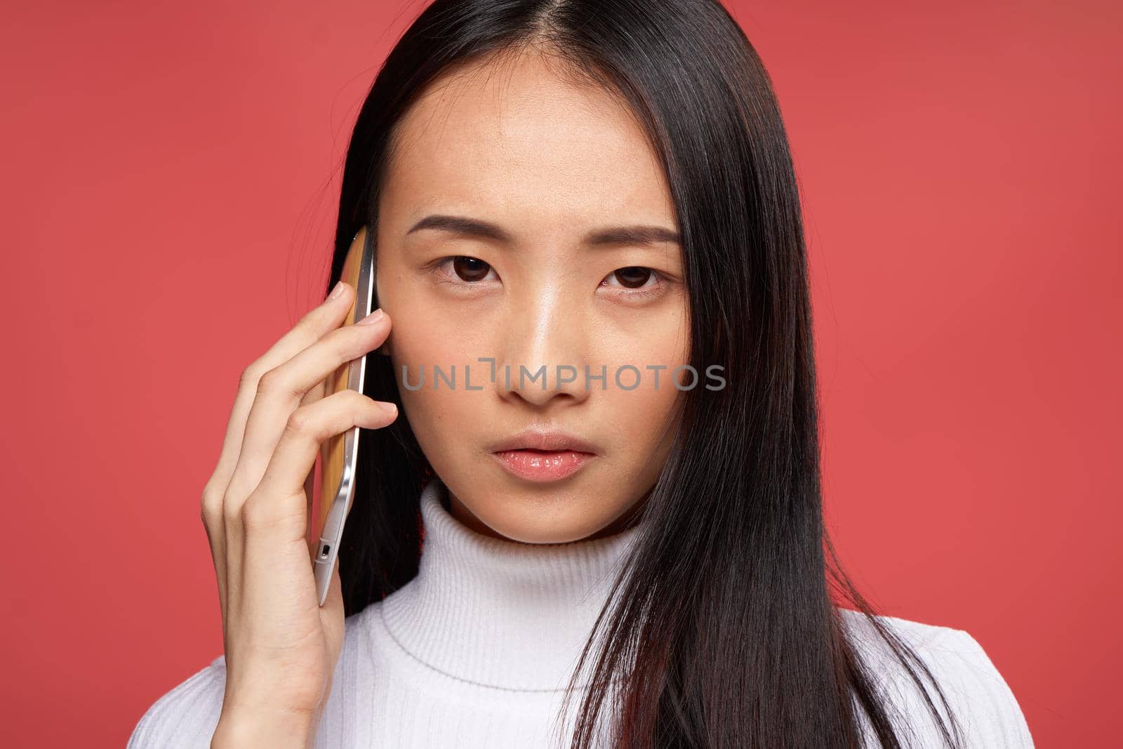 woman of asian appearance talking on the phone technology emotions red background. High quality photo