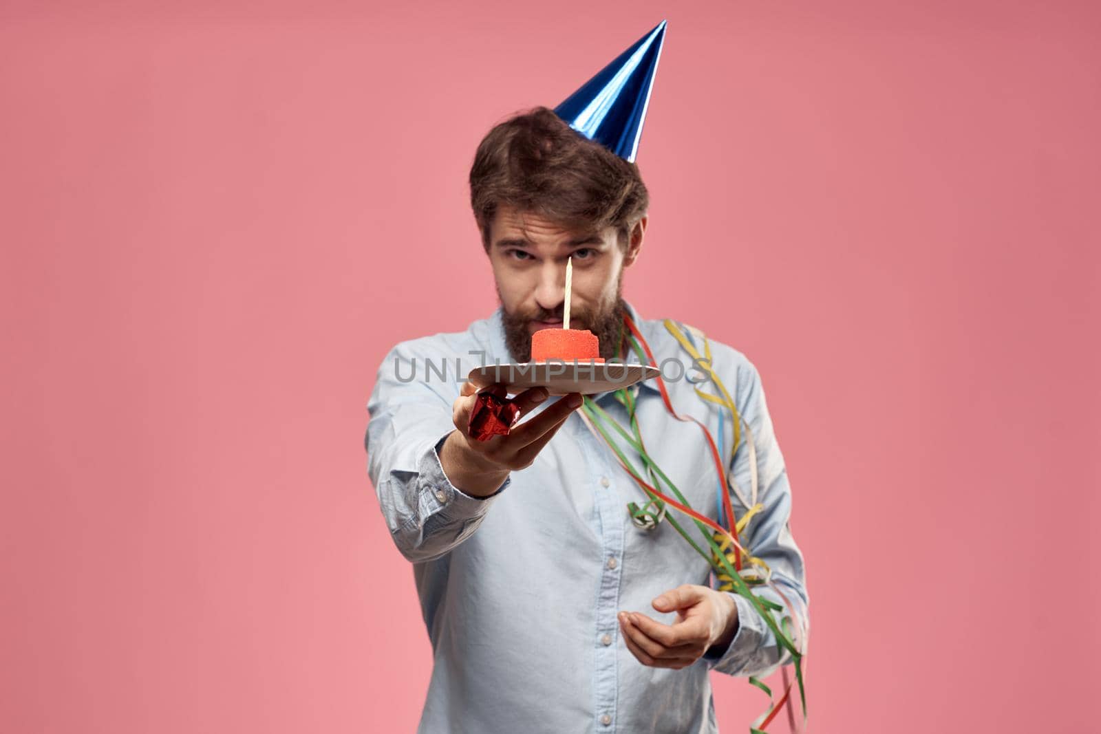 Man with cake in a plate and in a blue shirt on a pink background birthday holidays cropped view by SHOTPRIME