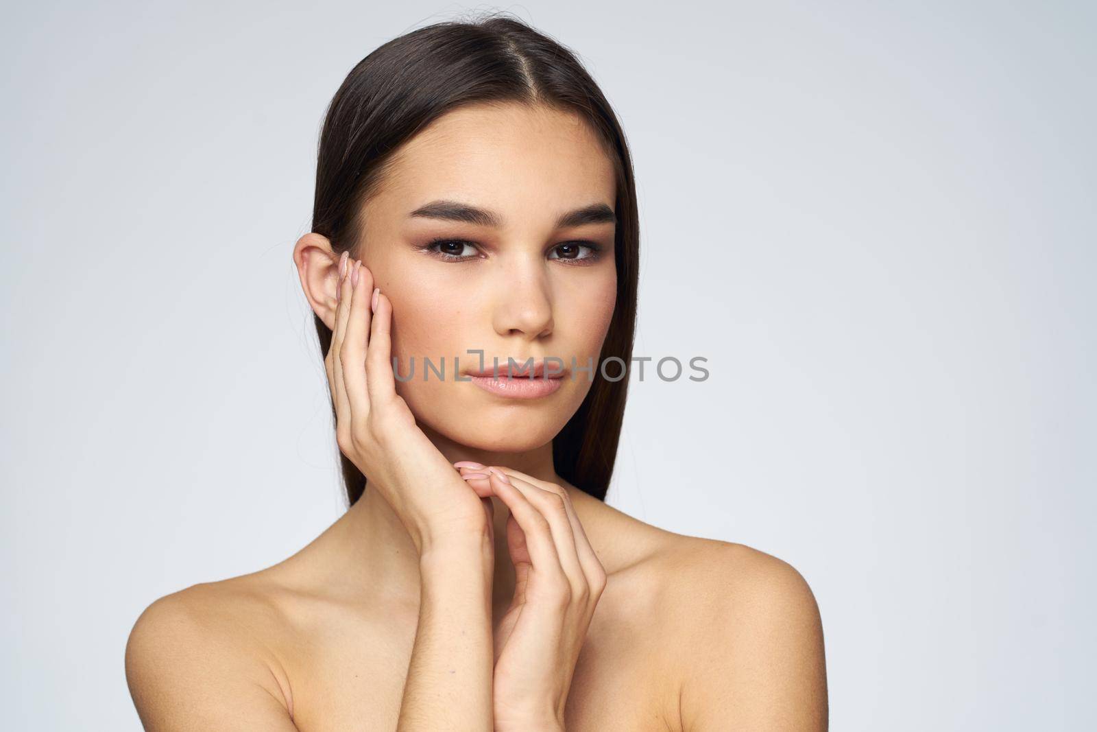 Woman with long hair bared shoulders clean skin body care light background. High quality photo