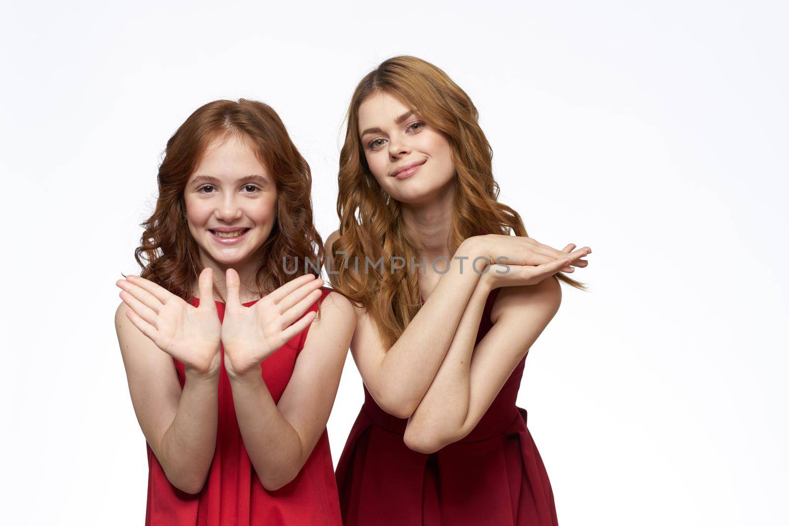 Mom and little daughter wearing red dresses joy friendship lifestyle light background. High quality photo
