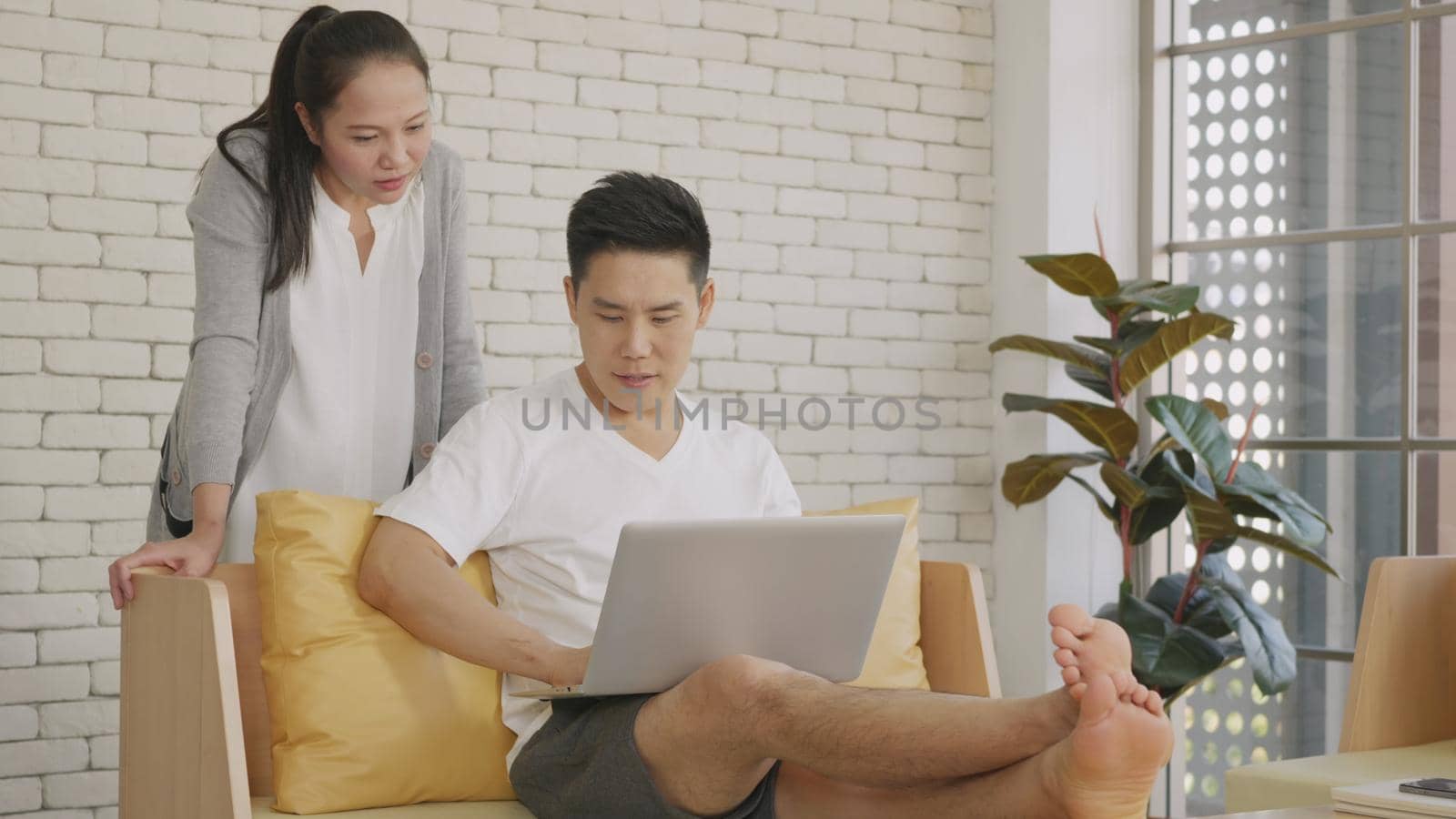 Asian family couple husband and wife work and using laptop computer analyzing finances discuss. Cheerful loving couple smile shopping order products online together from home by computer,