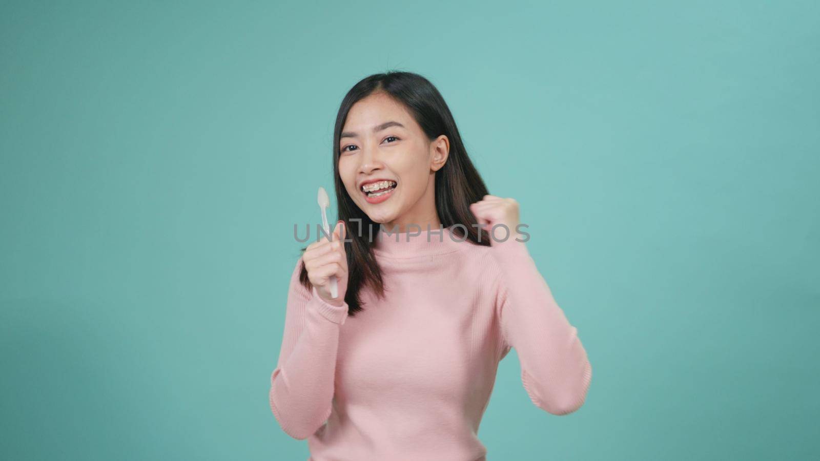 Asian young beautiful woman smile brushing teeth dancing enjoying music,  Female brush teeth singing song, dance and have fun isolated on blue background, lifestyle dental hygiene and health concept